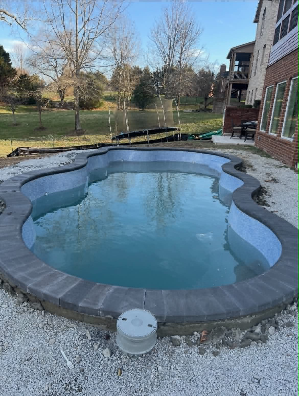 Freeform inground pool with dark stone coping and mosaic tile interior