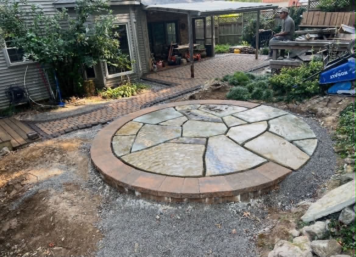 Round flagstone patio under construction with brick border