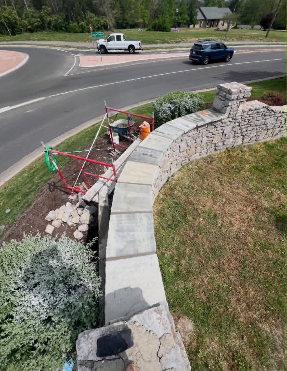 Curved roadside stone wall with matching stone caps and column
