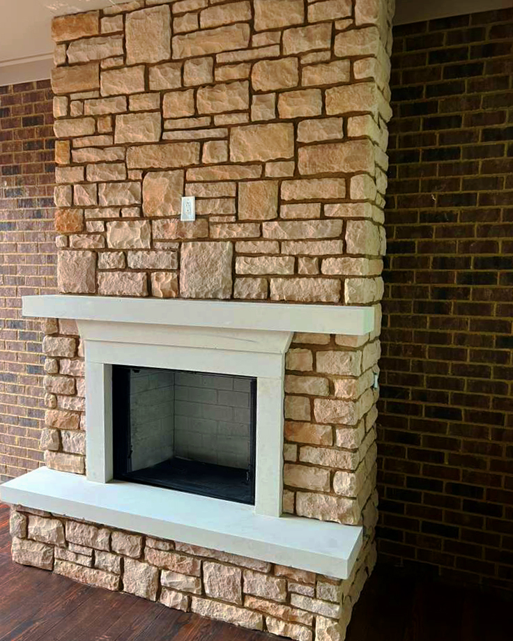 Floor-to-ceiling natural stone fireplace with cast stone mantel