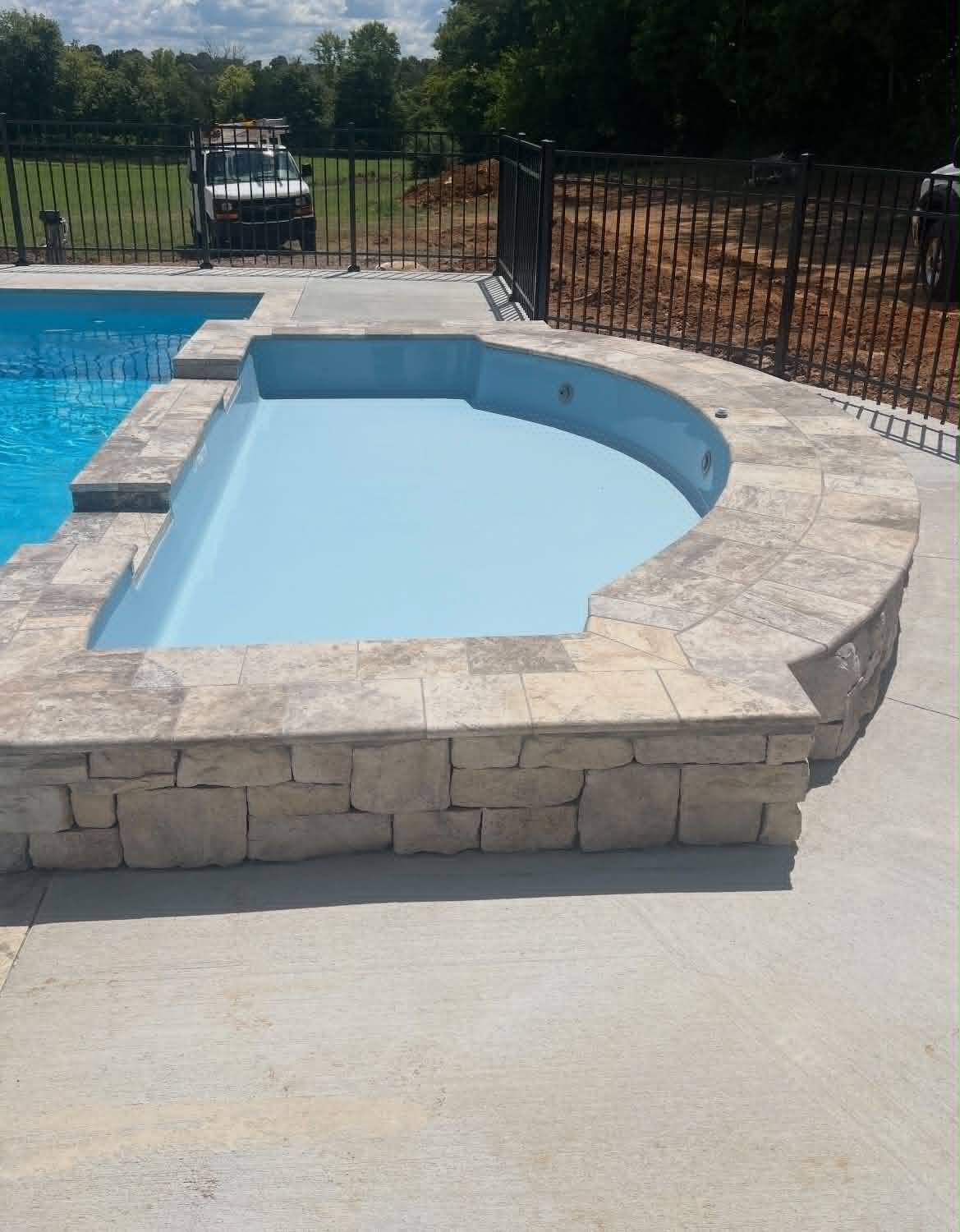Pool spa with light stone coping and block-style stone veneer base