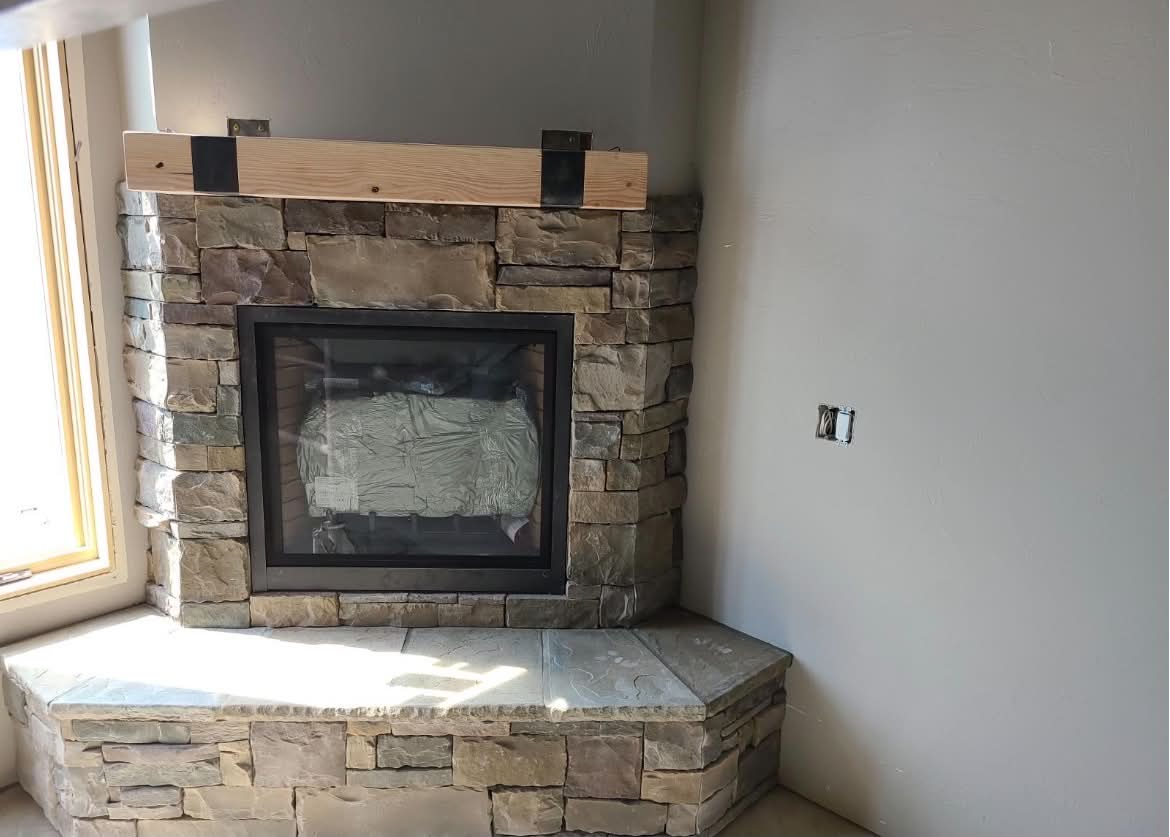 Corner stone fireplace with reclaimed wood mantel and flagstone hearth