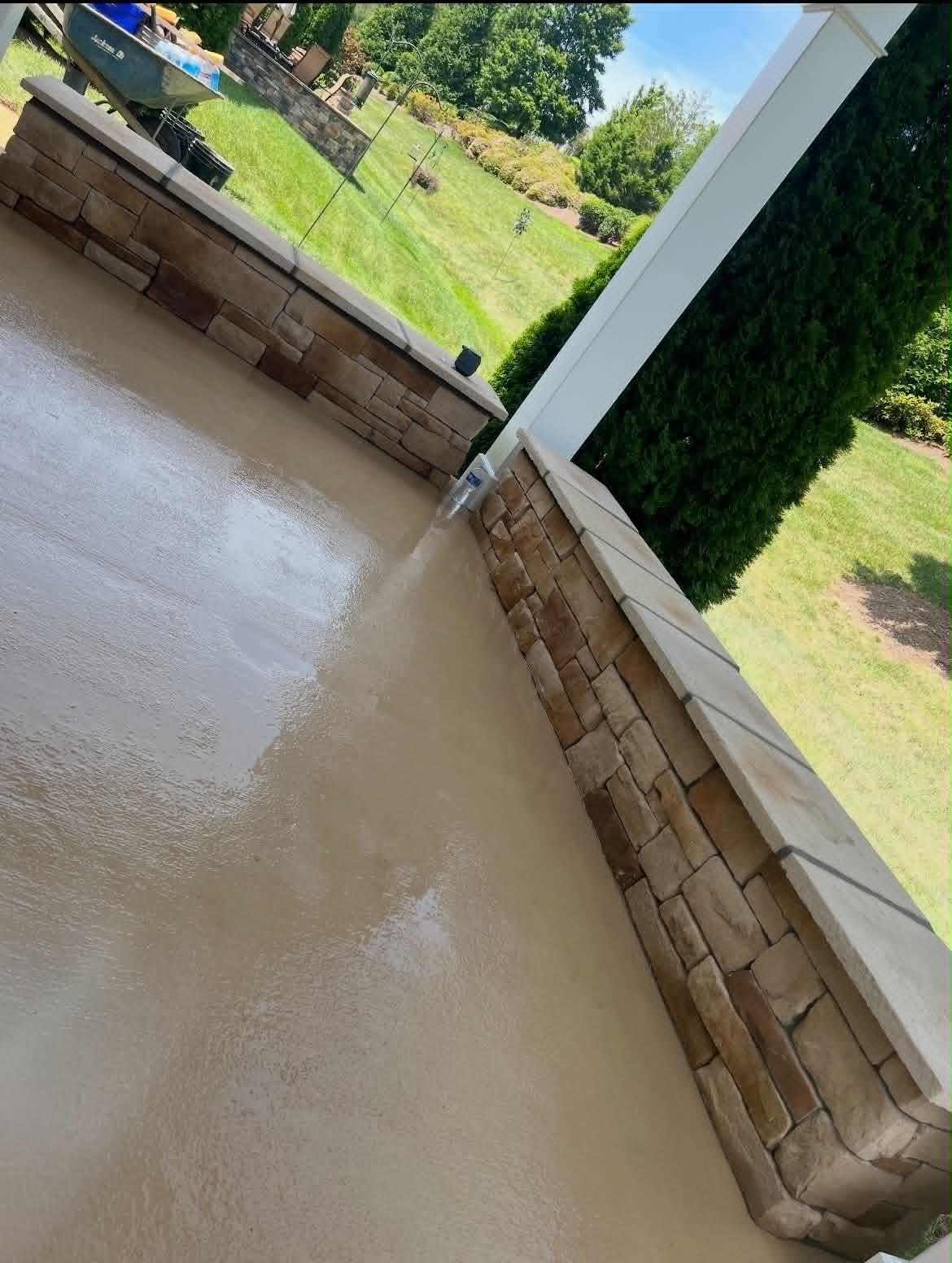 Fresh poured concrete patio with stone veneer pillar and cap detail