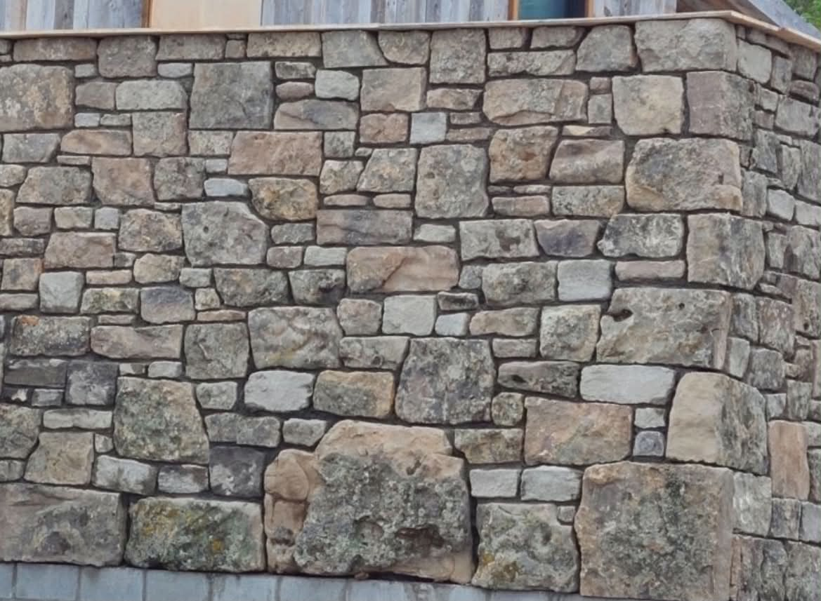 Dry-stack natural stone retaining wall with mixed earth-tone stones